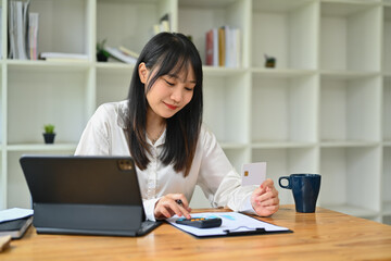 Young Asian woman hand calculating expenses and debt from credit card. E-commerce, financial planning and expenses