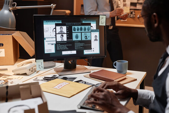 Closeup of male detective using computer at workplace and reading suspects personal profile on screen, copy space
