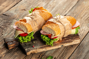 Healthy sandwich salami, tomato, lettuce and cheese on a wooden board. banner, menu, recipe place...