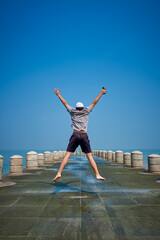 Tourists jumping happily on the pier at the Batu Ferringhi beach of Penang Island