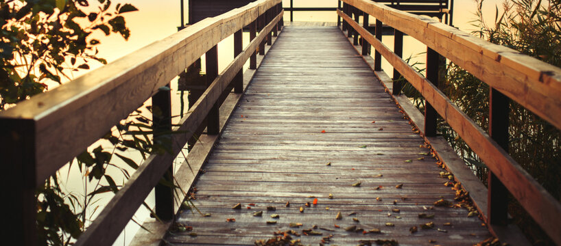sunset on a wooden pier. Autumn landscape with falling leaves