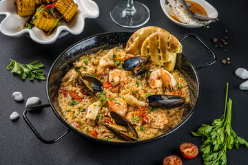 Italian Cuisine. Greek seafood and rice paella with shrimp, mussels and squid. Top view on a dark background