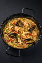 Italian Cuisine. Greek seafood and rice paella with shrimp, mussels and squid. Top view on a dark background