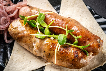 Turkish cuisine. Grilled beef sausages lie on a plate with pita bread and pickled onions