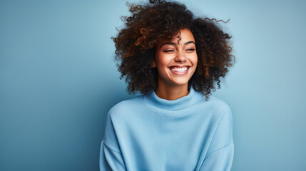 portrait of a strong, independent African American woman against a blue background while wearing a blue sweater - obrazy, fototapety, plakaty