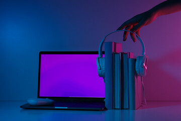 Books, headphones, laptop and female hand on gray background