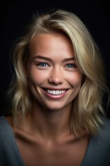 portrait of an attractive smiling blonde female against a gray background