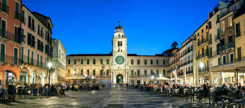Padua, Italy - October 1, 2023: Piazza dei Signori or Piazza della Signoria in the evening. The square is dominated by the famous Clock Tower. People sitting at the tables in the bar or walking around