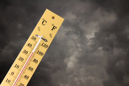 High temp thermometer on rain clouds background.Heat Illness.global warming effect.