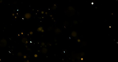 gold glow particles bokeh sparkle glittering on black background, holiday christmas new year celebration