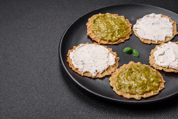 Round snacks with crispy chips or crackers with cream cheese and pesto