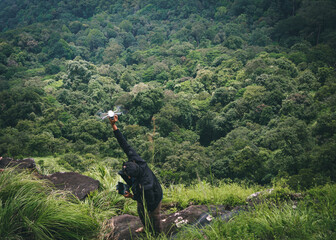 A drone operator picking a drone from the top of a green hill, shot on 02-10-2023,  Kodagu, Karnataka, India