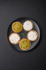 Round snacks with crispy chips or crackers with cream cheese and pesto