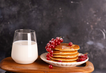 Delicious stack of pancakes with fresh berries and a glass with milk. 