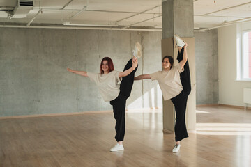 two girls doing synchrone acrobatic moves in the dance studio