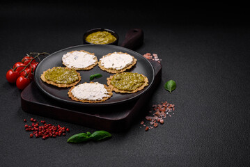 Round snacks with crispy chips or crackers with cream cheese and pesto