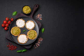 Round snacks with crispy chips or crackers with cream cheese and pesto
