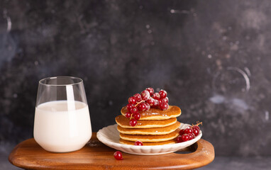 Delicious stack of pancakes with fresh berries and a glass with milk. 