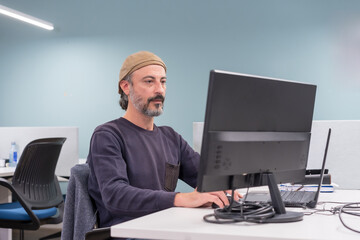 Serious stylish mature man using computer in a co-working