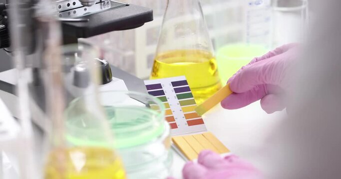 Scientist chemist checking acidity of liquid in petri dish using litmus paper in laboratory closeup 4k movie. Acid-base balance in liquids concept