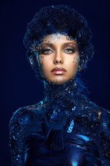 Closeup portrait of a girl with futuristic makeup with silver foil on her face and studio color lighting