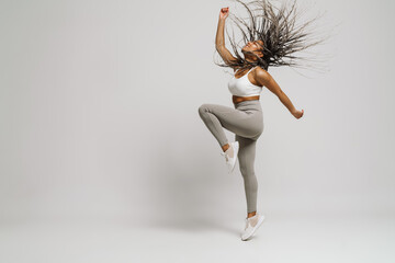 Beautiful african woman dancing isolated over white wall - obrazy, fototapety, plakaty