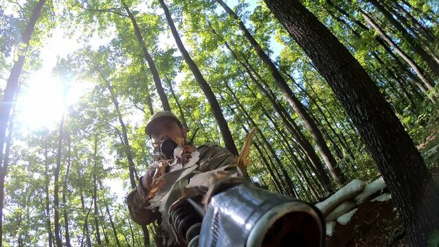 The camera on the bath of weapons. The military sniper in the helmet is attacking and assaulting the enemy in the forest. A close -up as a special forces to be in a weapon.