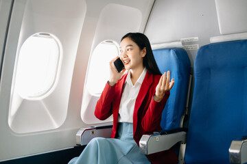Young Asian executive excels in first class, multitasking with digital tablet, laptop and...