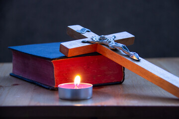 Holy Bible with wooden cross and burning candle. Religious background. 