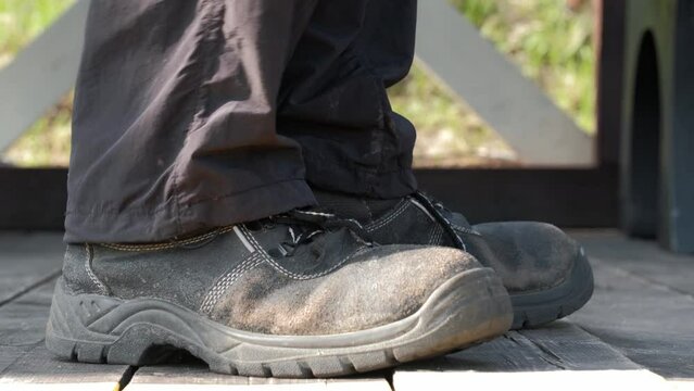 old worn out shoes on the feet closeup. a man stands on wooden planks and turns around, the backs of old shoes are visible. concept of poverty.