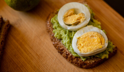  avocado toast topped with a perfectly boiled egg, presented on a rustic wooden board