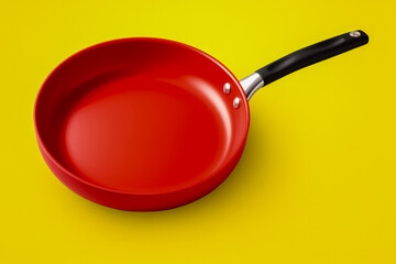 A bright red frying pan isolated on a gradient yellow background 