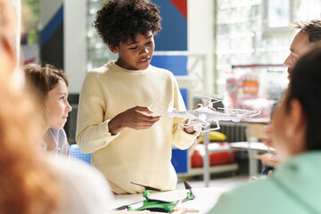 Boy trying to explain how quadcopter works in science class