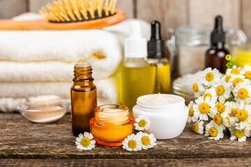 Chamomile spa. Composition with chamomile flowers, handmade soap, essential oil cosmetic bottle, body cream, scrub and sea salt on a white texture background. Relaxing beauty treatments.Copy space
