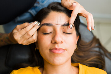 Beautiful mexican woman doing her eyebrows in the beauty room