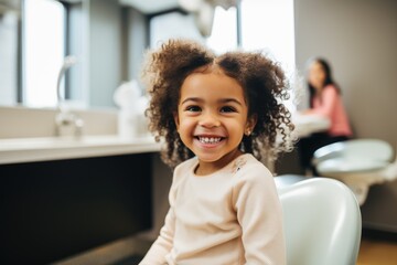 Smiling portrait of a young african american girl sitting in a dentists office - obrazy, fototapety, plakaty