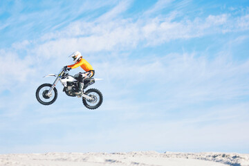 Motorbike, jump and man in the air with blue sky, mock up and stunt in sports with fearless person...