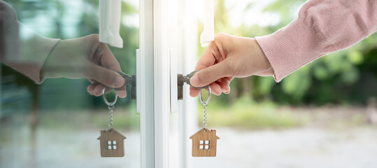 Landlord key for unlocking house is plugged into the door. Second hand house for rent and sale. Owner use hand unlock door mortgage for new home, buy, sell, renovate, investment, owner, estate - obrazy, fototapety, plakaty