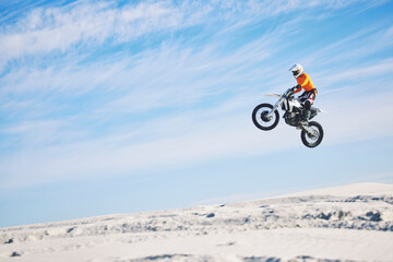 Motorcycle, desert and jump for sports in race, adrenaline and training for fitness in competition. Athlete, sky and mockup for freedom, driving and dirtbike in outdoor for stunt or performance - obrazy, fototapety, plakaty