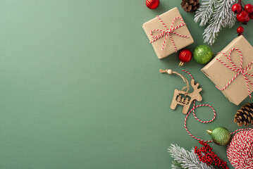 North Pole charm: Top-view image of kraft gift boxes, wrapping accessories, baubles, wooden deer ornament, mistletoe berries, pine cones and frosty greenery on a subtle green base for text or ads