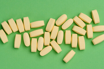Yellow oval tablets on a green background, top view