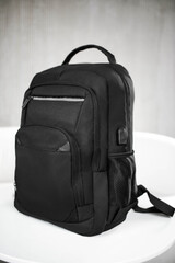 Naklejka premium A black backpack with pockets in the front stands on a white table