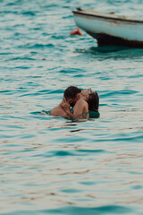 A romantic young couple sharing a passionate kiss amidst the serene beauty of the ocean at sunset.