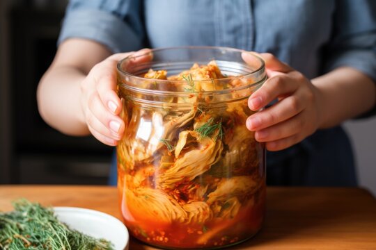 hand serving homemade kimchi from a glass jar