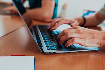 In a close-up view, the fingers of a man are seen typing swiftly on a laptop keyboard, depicting a scene of focused productivity in a digital work environment