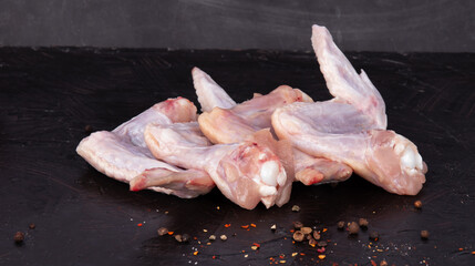 Fresh raw chicken wings for cooking on a black background. Raw Chicken Butchery