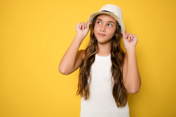 Obraz na płótnie Canvas Portrait of beautiful girl wearing straw hat standing isolated over yellow background.