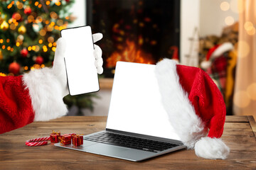 Notebook and smartphone with blank screen on rustic Christmas interior with fireplace. Christmas...