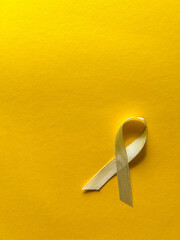 Cream ribbon on yellow background, cancer awareness, World Cancer Day, World Autism Awareness Day