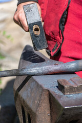 A blacksmith working a piece of iron while working on an anvil